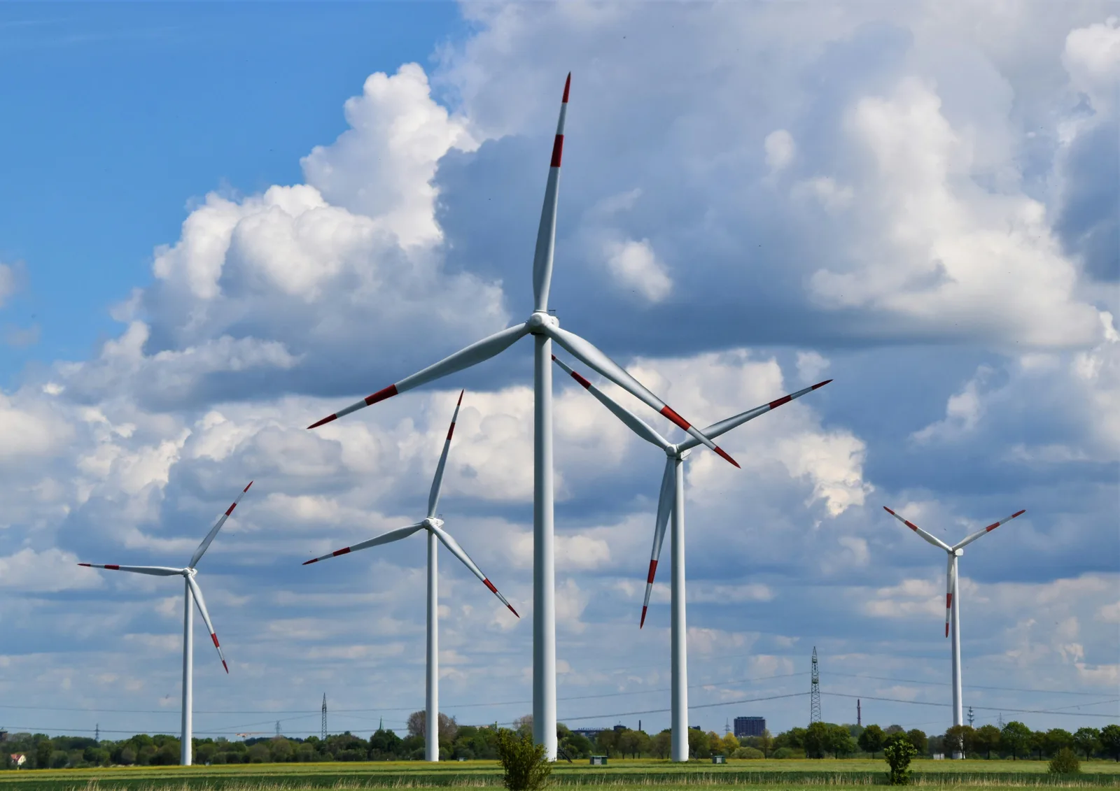A field of wind turbines under a blue sky with clouds
